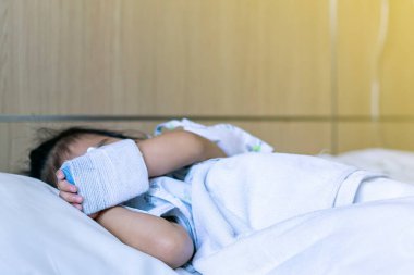 Çocuk ya da kız hasta dinlenir ya da yatağında ya da elinde uyur. Hala serum, vitamin ya da damar içi enjeksiyon için tıbbi malzemelerle kilitlidir.