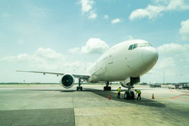 Uluslararası havaalanının terminal kapısında, bulutlu mavi gökyüzü arka planında, modern yolcu veya kargo uçağı otoparkında teknisyen ya da mühendis kontrolü