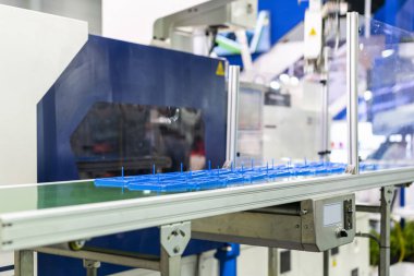 Fabrikadaki üretim sürecinde otomatik taşıma bandında plastik enjeksiyon küf makinesi tarafından üretilen birçok ürün veya ürün.