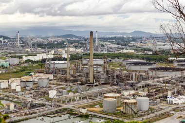 Petrol rafinerisi ve petrokimyasal sanayi tesisi olan tankın manzarası. Arka planda bulutlu gökyüzü ve akşam Chonburi Tayland 'da dağ.