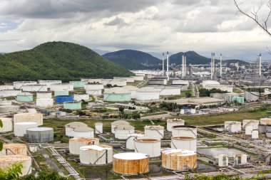 Petrol rafinerisi ve petrokimyasal sanayi tesisi olan tankın manzarası. Arka planda bulutlu gökyüzü ve akşam Chonburi Tayland 'da dağ.