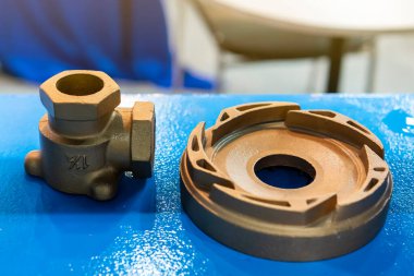 Industrial casting parts vane pump or propeller blades and water joint Brass fittings on blue table clipart