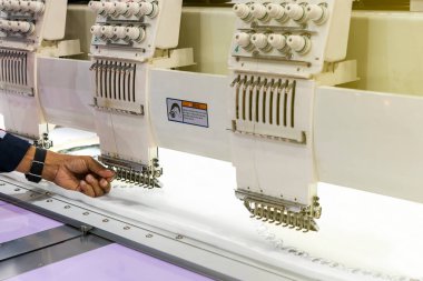 Sanayide tekstil veya giysi imalatı için modern ve otomatik yüksek teknoloji dikiş makinesi üzerinde çalışan operatör veya terzi