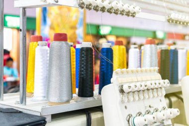 Modern ve otomatik yüksek teknoloji dikiş makinesine kurulmuş renkli pamuk makarası endüstriyel üretim sürecinde tekstil ya da giyim giyim için