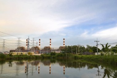 Doğal gaz elektrik santrali baca yığını ve Chonburi Tayland 'da su yansıması ve akşama yakın güzel gökyüzü olan bir sürü direk.