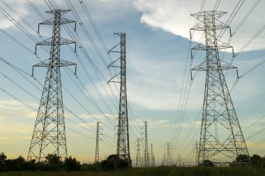 Bir sürü yüksek voltajlı elektrik direği ve güzel gökyüzü olan hatlar akşama yakın.