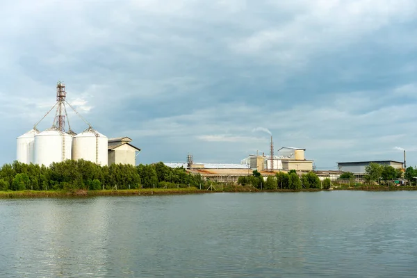 Akşamları deniz kıyısında bulutlu gökyüzü olan büyük sanayi ve silo binaları.
