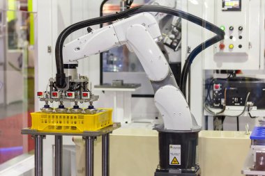 Çalışırken hassas ve hassas endüstriyel robot kolu. Fabrikada otomatik vakum tutacağı olan plastik kutuya cam şişe koy.