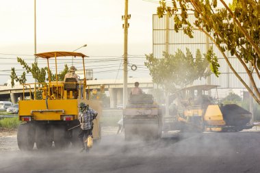 Birçok işçi ya da işçi, yol silindirli, asfalt sıkıştırıcı, sıcak hava buharı ile birlikte yol yapımına ya da kaldırımlarına yardım etti.