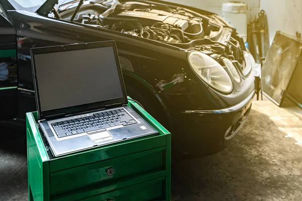 laptop or computer notebook interfaced with car for repair during work investigate cause of problem (program and electric system check) or working on automobile gasoline or diesel engine at garage