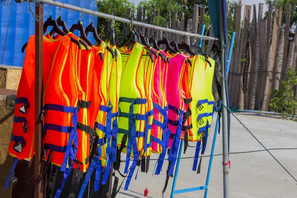 many colorful life jacket or life vest hanging on a clothesline