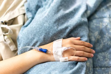 Bir hastanın eline odaklan ya da hastane koğuşundaki hastaya damardan serum ve vitamin verilmesi sırasında yatağa odaklan.