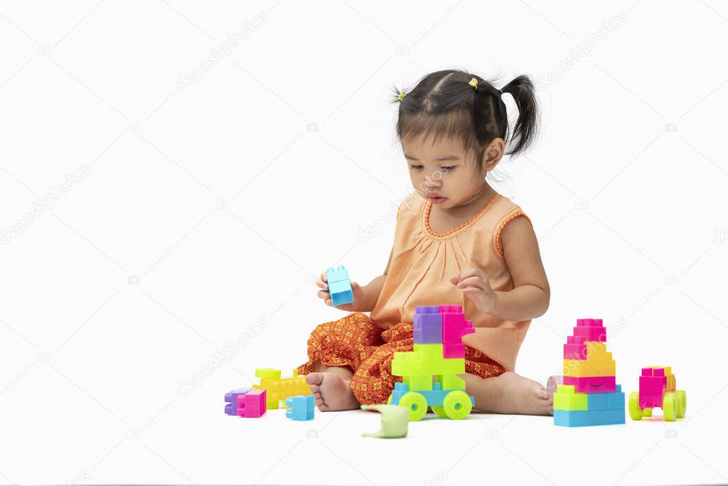 Asian child girl in Thai traditional dress sit and play colorful plastic blocks or toy happily isolated on white background