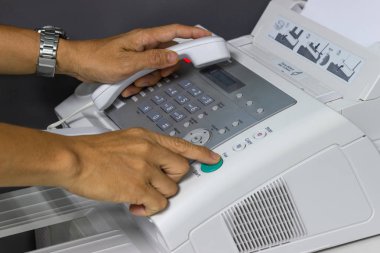 Elini adam ofiste bir faks makinesi kullanarak. İş kavramı 