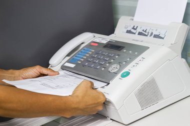 Elini adam ofiste bir faks makinesi kullanarak. İş kavramı 