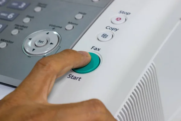 Finger pressing start button on the fax, business concept.