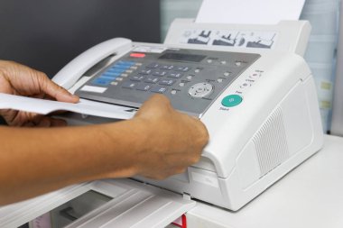 Elini adam ofiste bir faks makinesi kullanarak. İş kavramı 