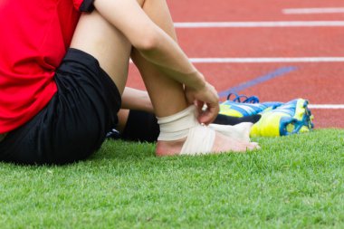 adam bir futbolcu, spor yaralanmaları ayak bileği yaralanması üzerine bandaj sıkıştırma uygulama.