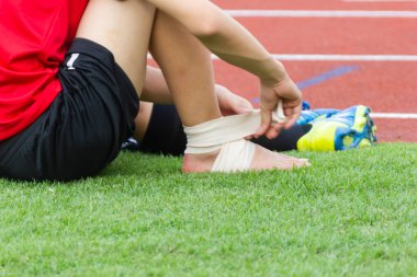 Erkek atlet sıkıştırma bandaj bir futbolcu, spor yaralanmaları ayak bileği yaralanması üzerine uygulama.