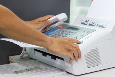 Elini adam ofiste bir faks makinesi kullanarak. İş kavramı 