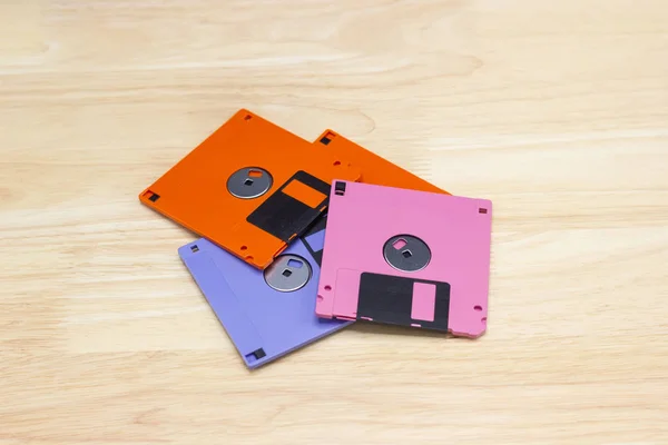 A floppy disk also called a floppy, diskette, or just disk was a ubiquitous form of data storage and exchange from the mid-1970s into the mid-2000, on wood background.
