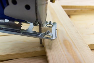 Tahtayı kesme işlemine başlamak için tahtayla elektrikli testereyi yakın çekim yap