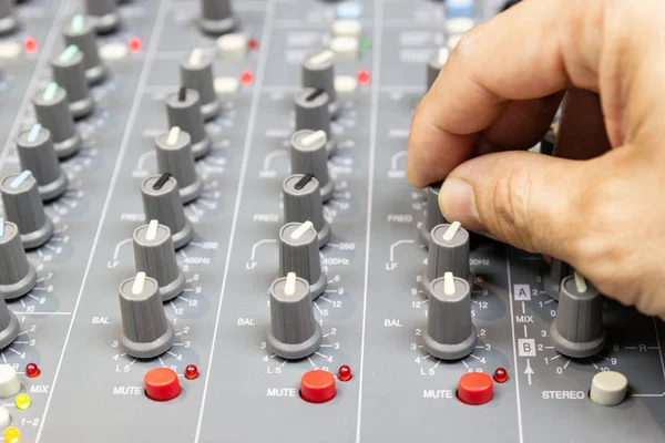 Men's hands are controlling the console of a large hi-fi system. Sound equipment. Control panel of a digital studio close-up mixer.