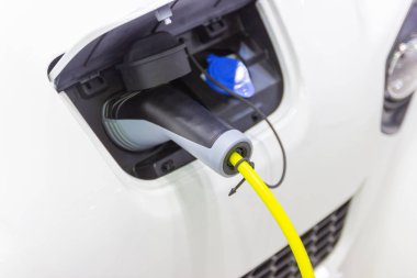 Aracın aküsünü şarj etmek yeni otomotiv yenilikleri şarj edilen elektrikli bir arabaya takılan güç kaynağı, enerji yeniliği kavramı..