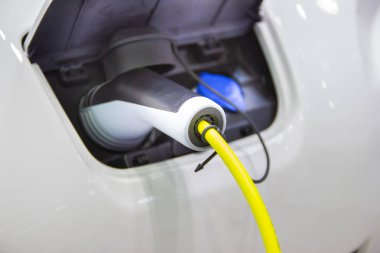 Aracın aküsünü şarj etmek yeni otomotiv yenilikleri şarj edilen elektrikli bir arabaya takılan güç kaynağı, enerji yeniliği kavramı..