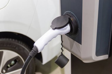 Aracın aküsünü şarj etmek yeni otomotiv yenilikleri şarj edilen elektrikli bir arabaya takılan güç kaynağı, enerji yeniliği kavramı..