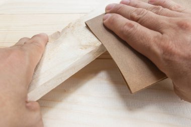 İşçi adam zımpara kağıdını cilalıyor elle ahşap.