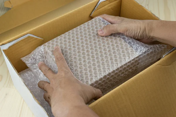 Mão de homem segurar bolhas cobrindo a caixa por bolha wrap para pro — Fotografia de Stock
