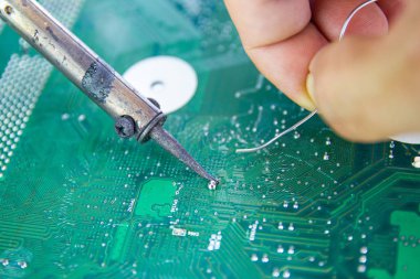 Teknisyenler elektronik tamir için bir lehimleme demir kullanıyor 