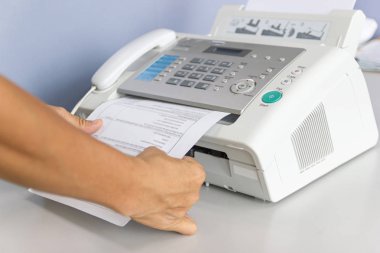 El adam ofiste bir faks makinesi kullanıyor 