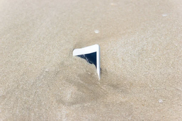 Fehér mobil telefon úszott a tengerbe a strandon. — Stock Fotó