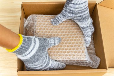 İnsan eli baloncuk ambalajını tutar, koruma paketi kırılır ya da geçiş sırasında sigorta yapılır.