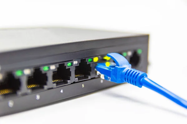 Kabel jaringan biru menghubungkan saklar port pada tabel putih — Stok Foto