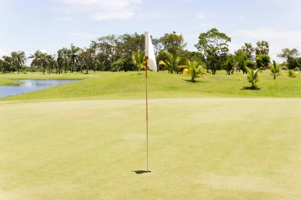 Bandeira branca no campo de golfe de em verde com céu azul — Fotografia de Stock