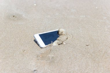 Sahilde denize yüzen beyaz cep telefonu.