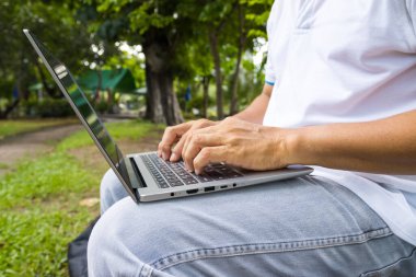Bir adam dizüstü bilgisayarda daktilo kullanıyor park konsepti çalışma alanı ve uzaktan kumandalı internet işi.