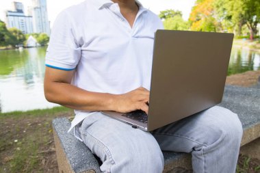 Bir adam dizüstü bilgisayarda daktilo kullanıyor park konsepti çalışma alanı ve uzaktan kumandalı internet işi.