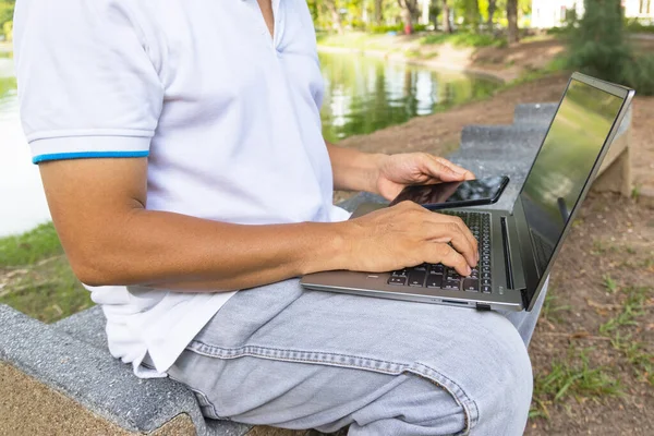 Een Man Typt Een Laptop Toetsenbord Gebruikt Mobiele Telefoon Het — Stockfoto