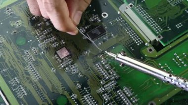 Teknisyenler bilgisayar devresi donanımının elektronik devre konseptini tamir etmek için lehim makinesi kullanıyorlar..
