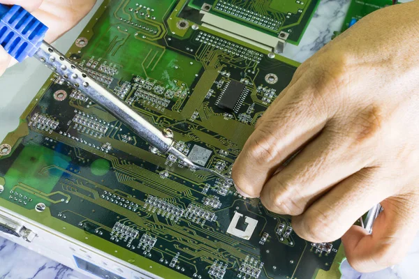 Technicians are using a soldering iron for repairing electronic of the computer circuit board concept technology of computer circuit hardware.