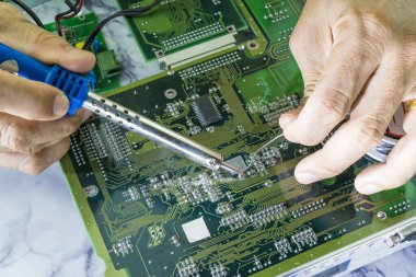 Teknisyenler bilgisayar devresi donanımının elektronik devre konseptini tamir etmek için lehim makinesi kullanıyorlar..