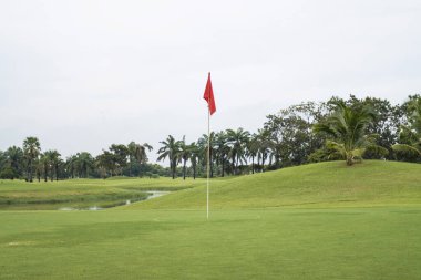 Golf sahasında yeşil çimde kırmızı bayrak