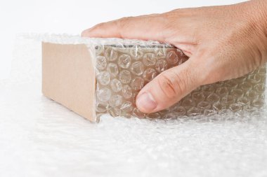 İnsan eli baloncukla kaplı kutunun üzerindeki baloncuklardan tutun koruma ürünü çatladı ya da sigortalı geçiş sırasında izole beyaz arka plan