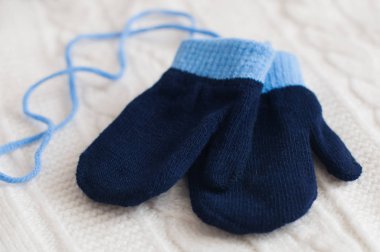 Beyaz yün kumaş üzerinde mavi örme eldiven çifti. Kış arka plan.