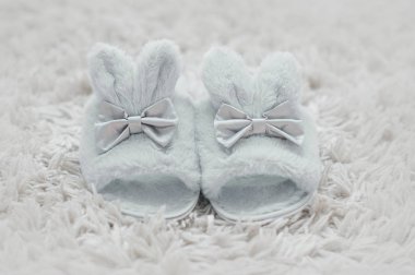 Beyaz kürklü halı üzerinde tavşan şeklinde güzel kürk terlik.