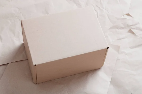 Caja de cartón marrón colocada en hojas de papel kraft arrugado . — Foto de Stock